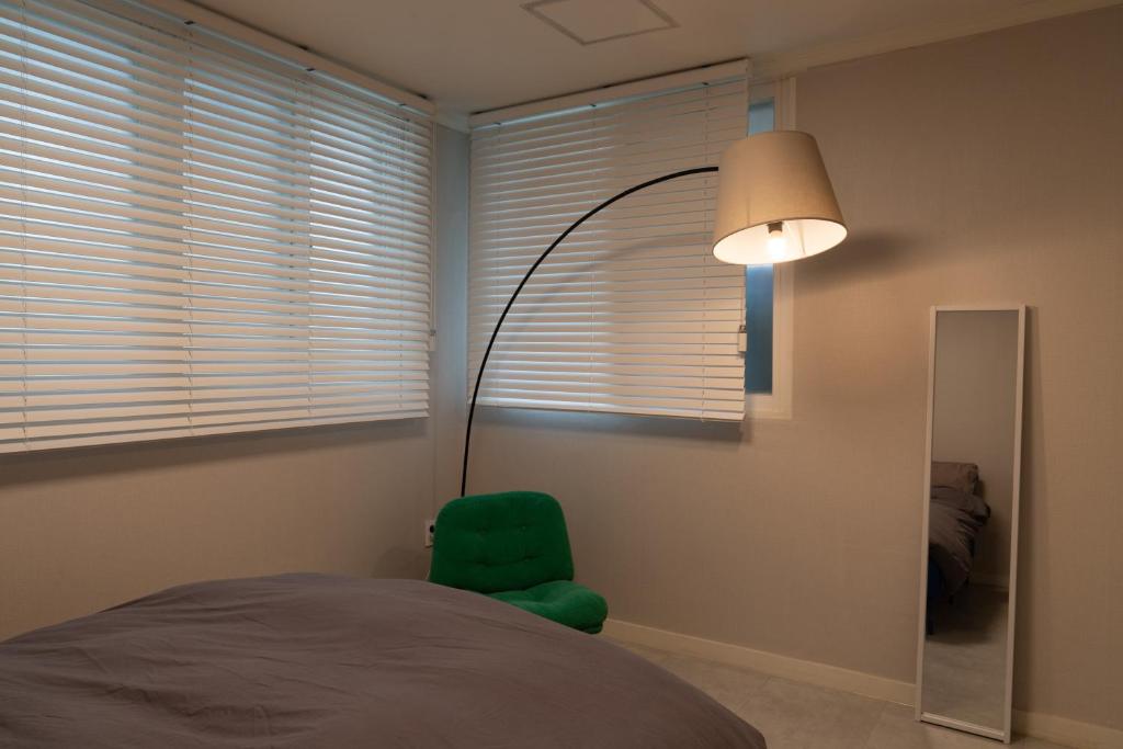 a bedroom with a green chair and a lamp at Manoa Garden in Seoul
