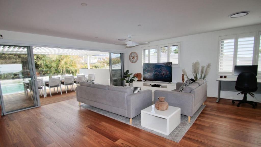 a living room with two couches and a television at The Pool House - Light and Spacious in Wamberal