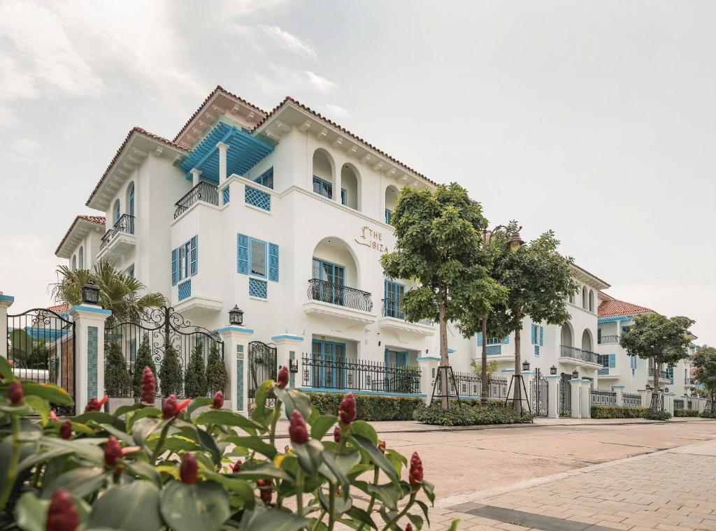 a white building with blue windows and a plant at The IBIZA in Ha Long