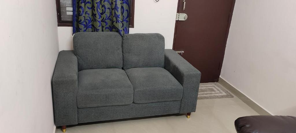 a gray couch sitting in a living room at "Ambi's stay " A unique and Secluded Nest with serene calmness views on a Traffic-Free Street at Bommasandra 3 km from Narayana Hrudayalaya Hospital in Bangalore