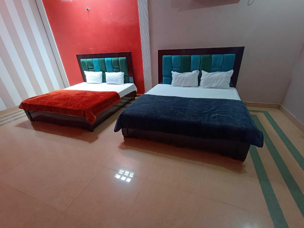 two beds in a room with red and blue at Hotel O Home Shri Hari Lodge Homestay in Ayodhya