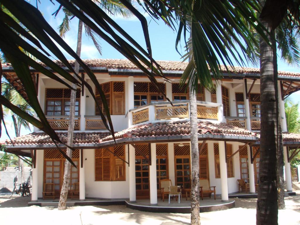 a building with palm trees in front of it at Stardust Beach Hotel in Arugam Bay