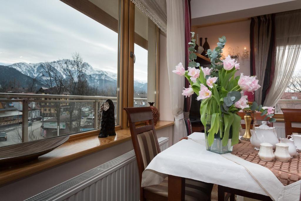 un jarrón de flores sobre una mesa en una habitación con ventana en VIP Apartamenty Jagiellonska 33a, en Zakopane