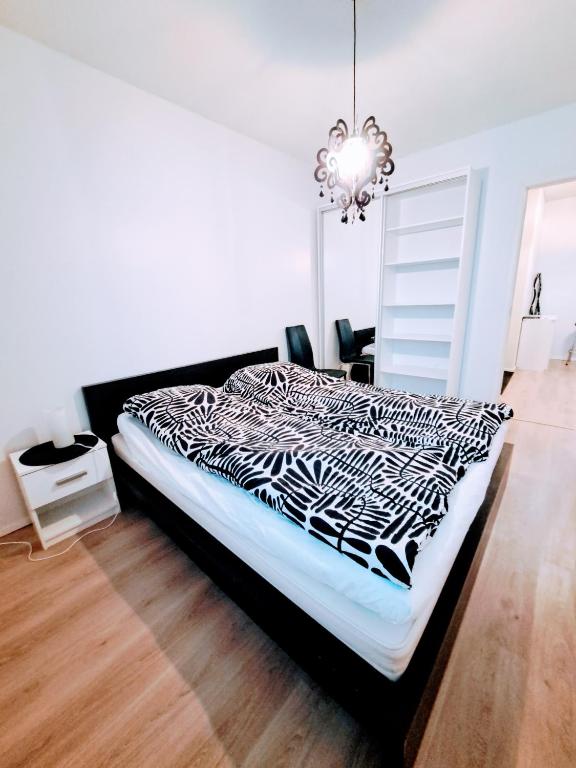 a black and white bed in a room with a chandelier at Spacious Northern City Apartment in Rovaniemi