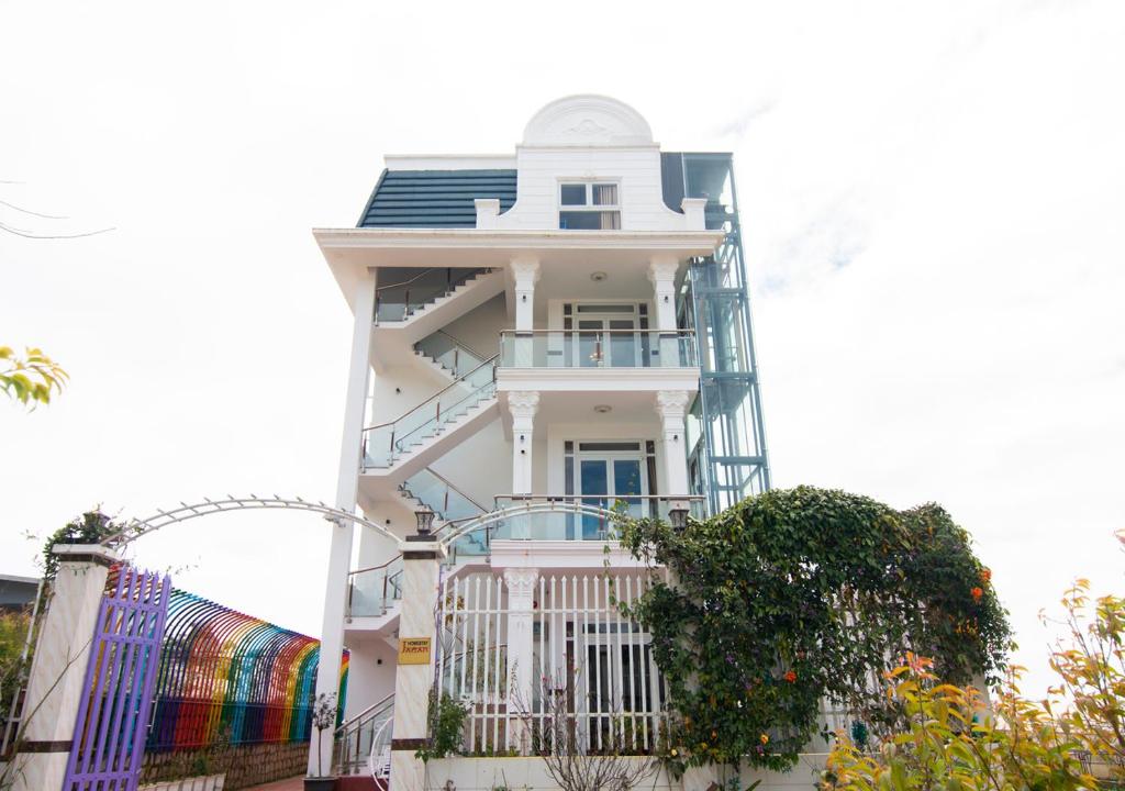 a white house with a balcony on the side of it at Villa Say Nắng Đà Lạt in Da Lat