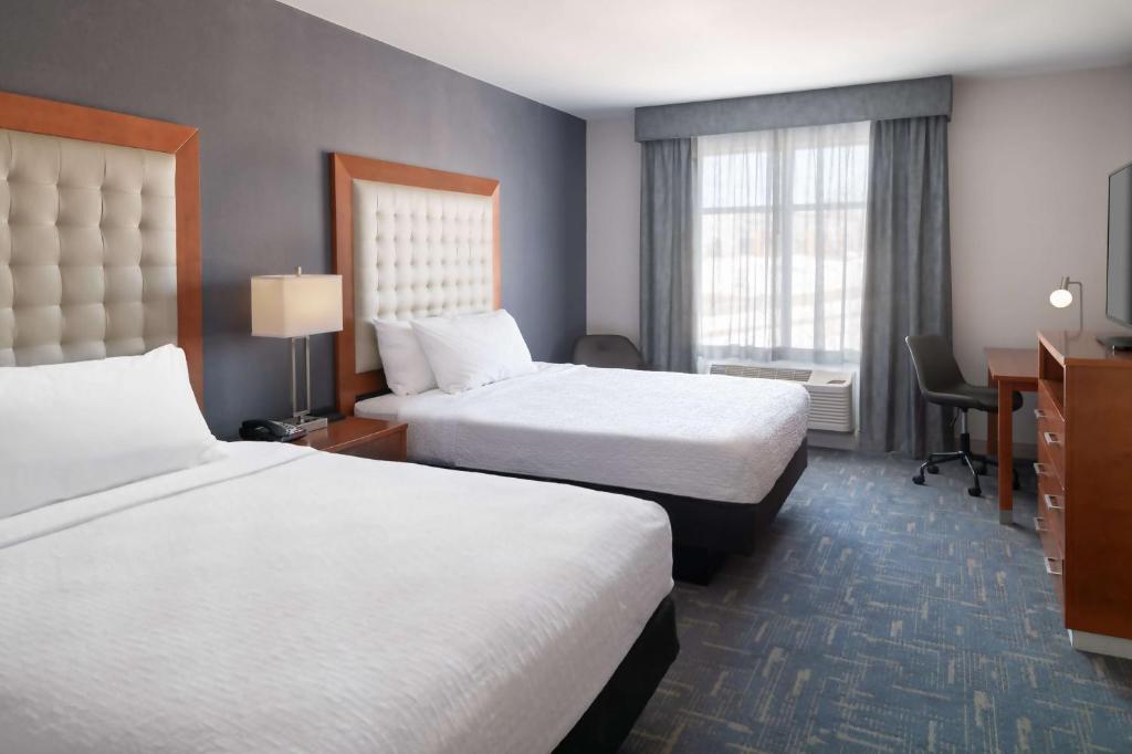 a hotel room with two beds and a desk at Homewood Suites by Hilton Gateway Hills Nashua in Nashua