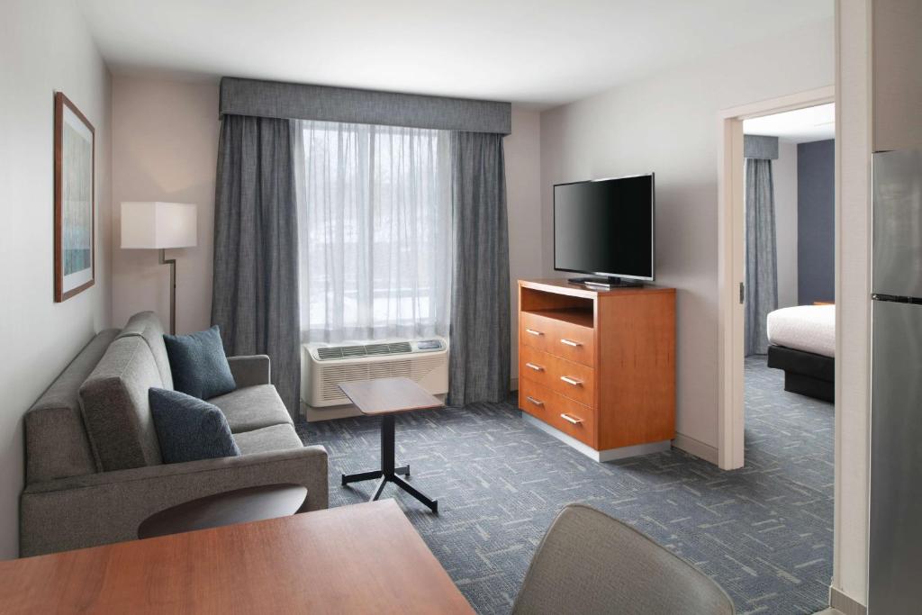 a hotel room with a couch and a television at Homewood Suites by Hilton Gateway Hills Nashua in Nashua