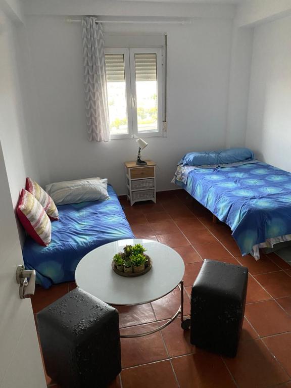 a living room with two beds and a table and a table sidx sidx at Habitación luminosa en piso compartido in Mairena del Aljarafe