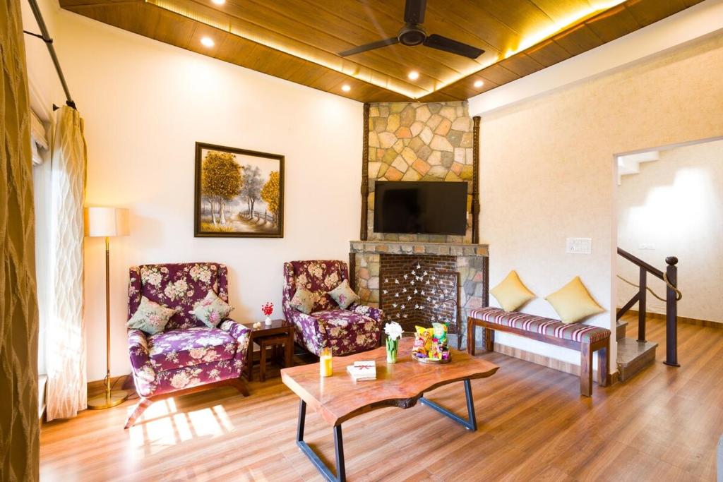a living room with two chairs and a fireplace at 3-BHK Retreat with Picturesque Balcony & Patio in Rājpur