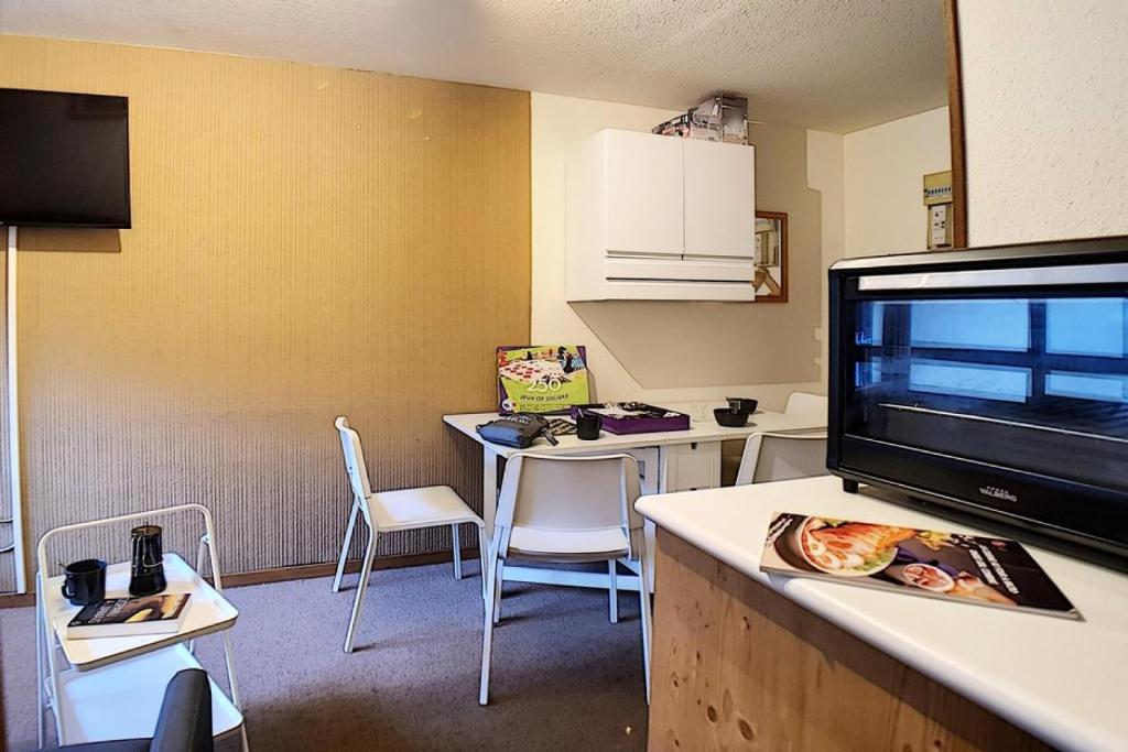 Il comprend un salon doté d'une télévision et d'une table avec des chaises. dans l'établissement Résidence Astragales - Studio cabine classique · Proche des pistes MAE-1671, aux Menuires