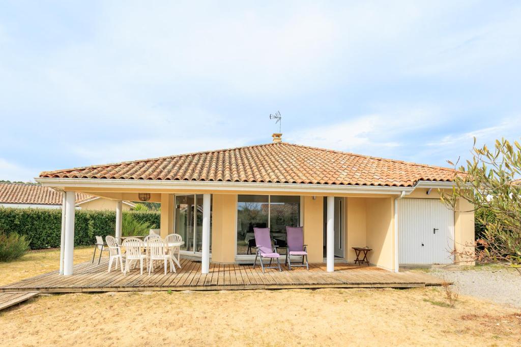 une maison avec une terrasse et des chaises violettes dans l'établissement Villa Rauzy, à Moliets-et-Maa