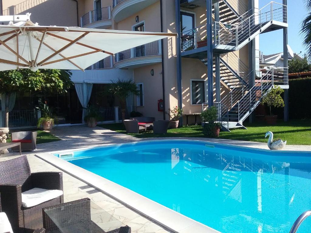 a swimming pool with an umbrella next to a building at Gullo Hotel in Curinga