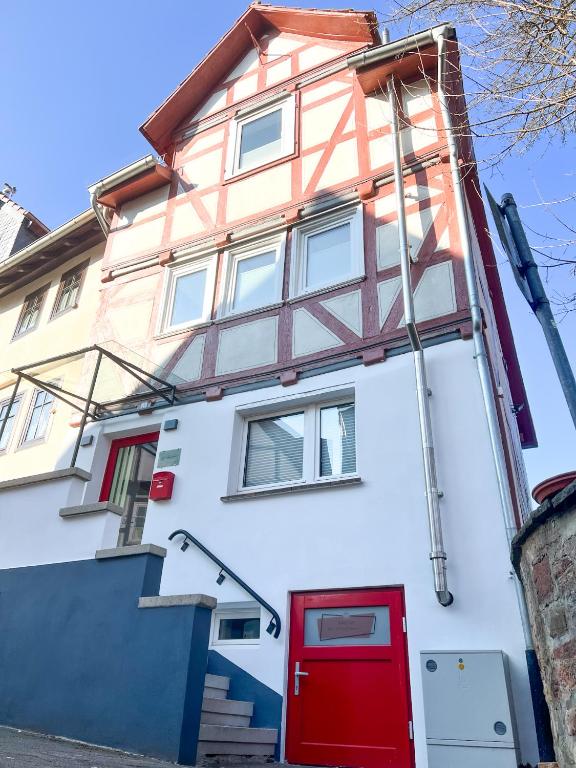 a white building with a red door and stairs at Casa BACCO in Rotenburg an der Fulda