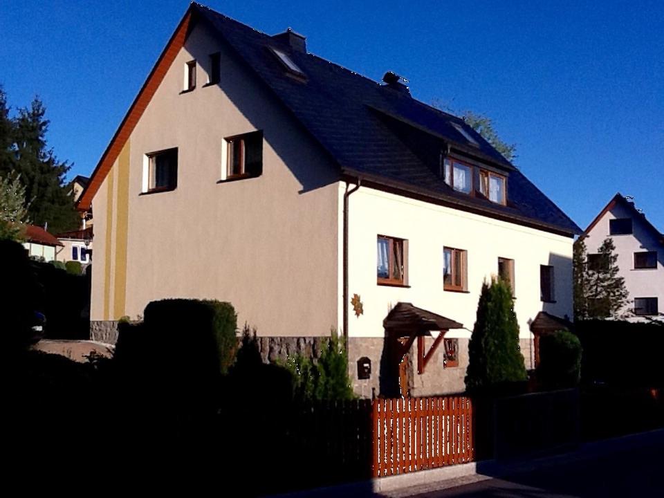 a white house with a black roof and a fence at Ferienhaus Günther in Aue