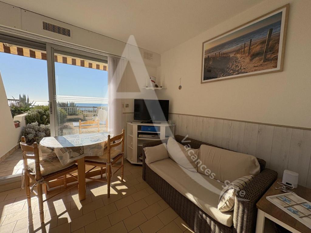 un salon avec un canapé et une table avec une télévision dans l'établissement T2 en rez de jardin, face a la mer avec parking, à Sète