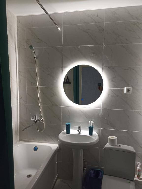 ein weißes Badezimmer mit Waschbecken und Spiegel in der Unterkunft ЖК Панорама Парк in Qostanai