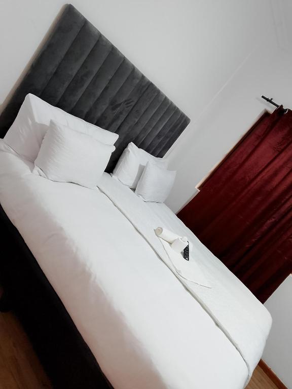 a large white bed with a black headboard and white pillows at Duminy Guest Lodge in Bellville