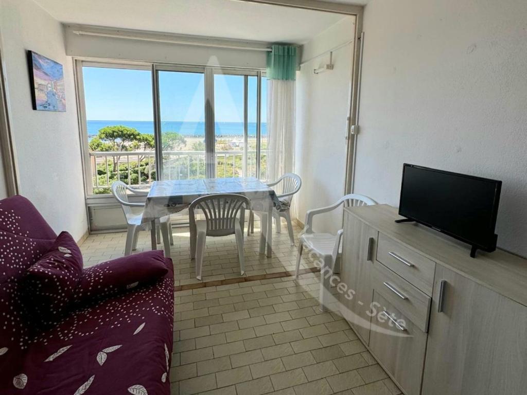 - un salon avec une table, un canapé et une télévision dans l'établissement Studio cabine avec parking, face a la mer, à Sète