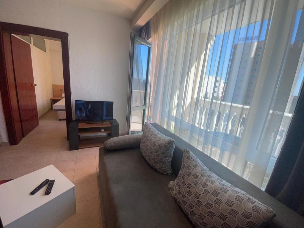 a living room with a couch and a large window at Miramar Apartment in Sunny Beach