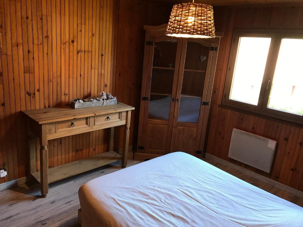 a bedroom with a bed and a table and a chandelier at Refuge des cimes in Xonrupt-Longemer