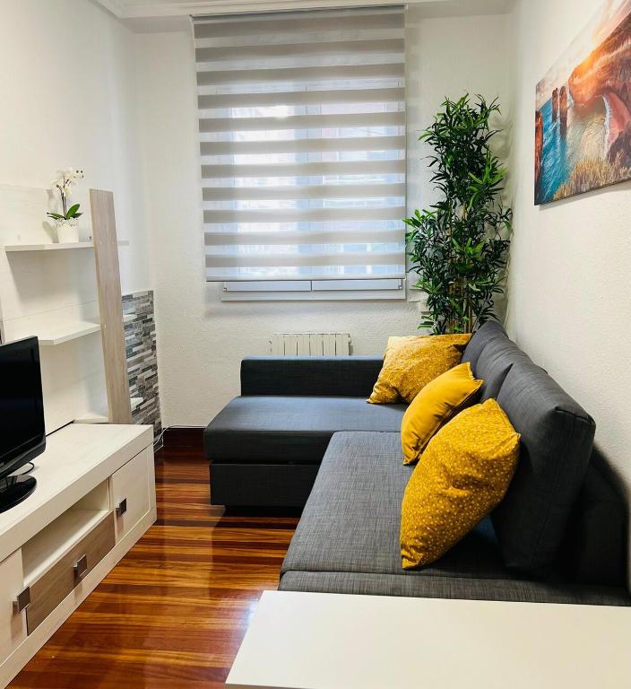 a living room with a black couch and yellow pillows at Apartamento El Pedregal in Castro-Urdiales
