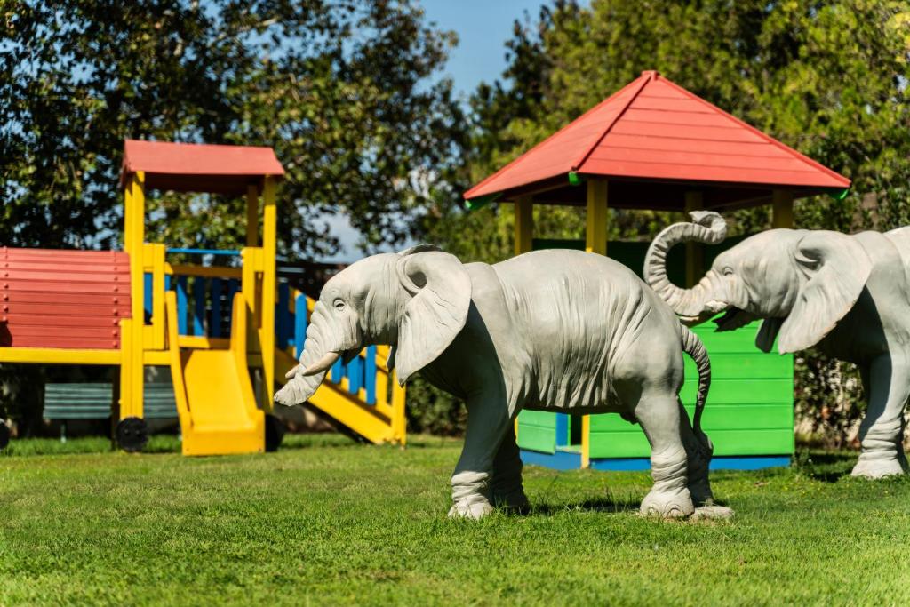two elephant statues standing in front of a playground at Plaza Resort in Anavyssos