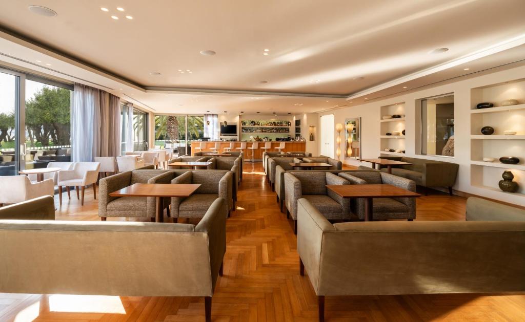 a restaurant with couches and tables and windows at Plaza Resort in Anavyssos