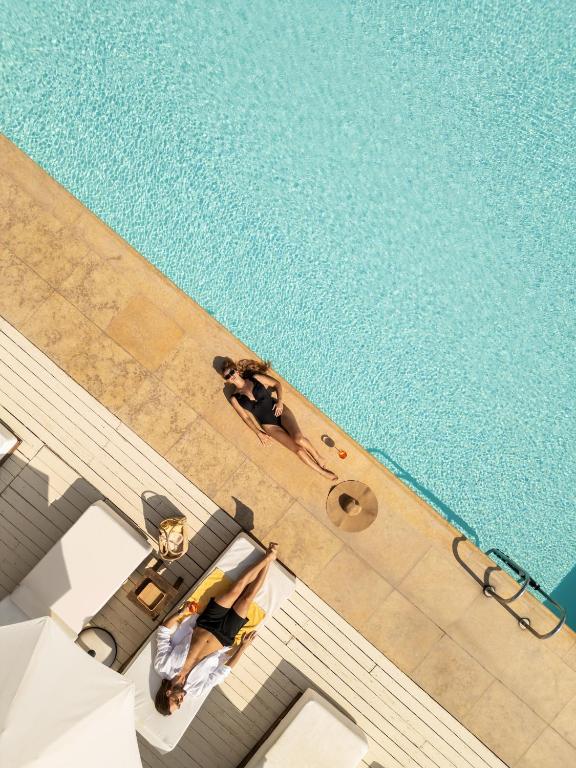 an overhead view of a swimming pool with two people sitting at Plaza Resort in Anavyssos