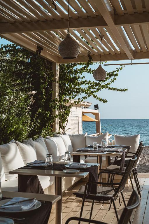 a patio with tables and chairs and the ocean at Plaza Resort in Anavyssos