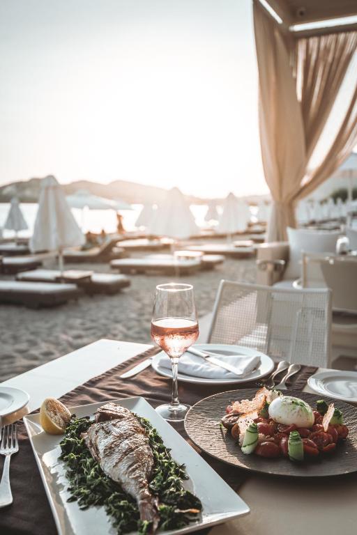 a table with a plate of food and a glass of wine at Plaza Resort in Anavyssos