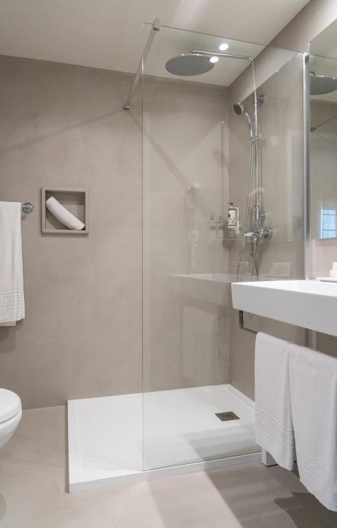 a bathroom with a glass shower and a sink at Costa d'Oiro Ambiance Village in Lagos