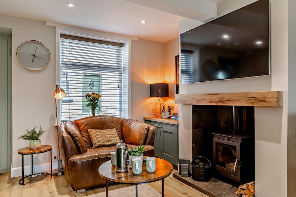 a living room with a leather chair and a fireplace at Charming Cosy Cottage in Bollington Village in Bollington