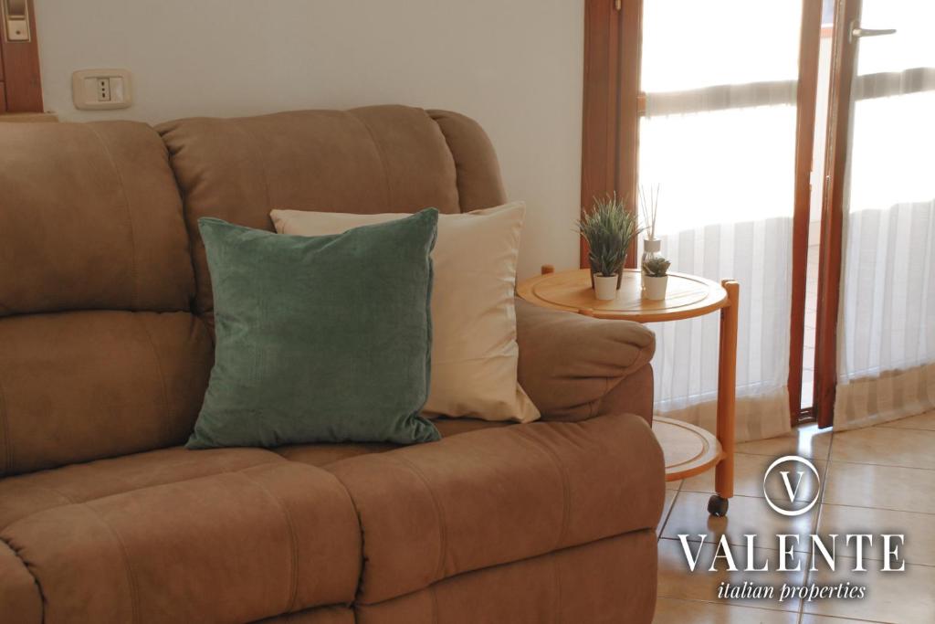 a brown couch with a green pillow in a living room at Cozy apartment in Follonica in Follonica
