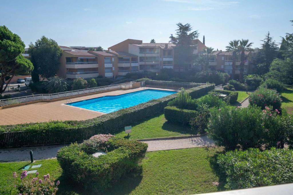 - une piscine dans une cour avec des buissons et des arbres dans l'établissement T2 cabine rénové/Piscine/Clim/commerces, au Lavandou