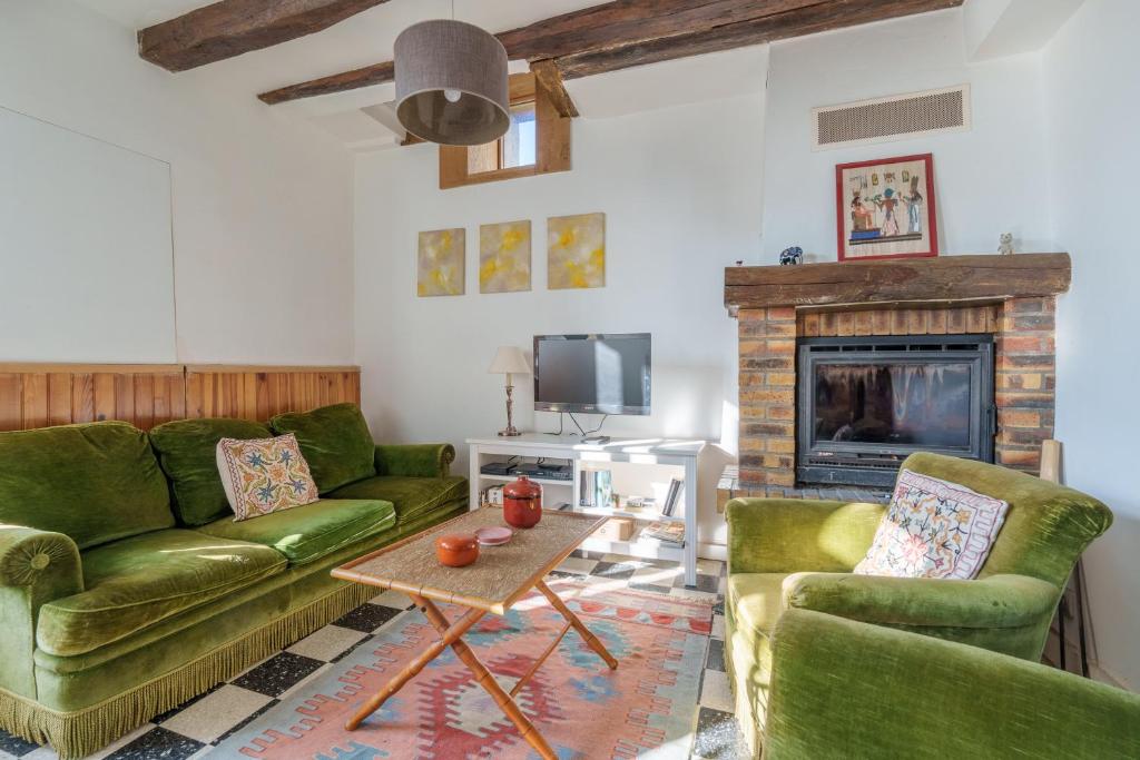 a living room with green couches and a fireplace at L'Avallonnaise - Au cœur de la Bourgogne in Avallon