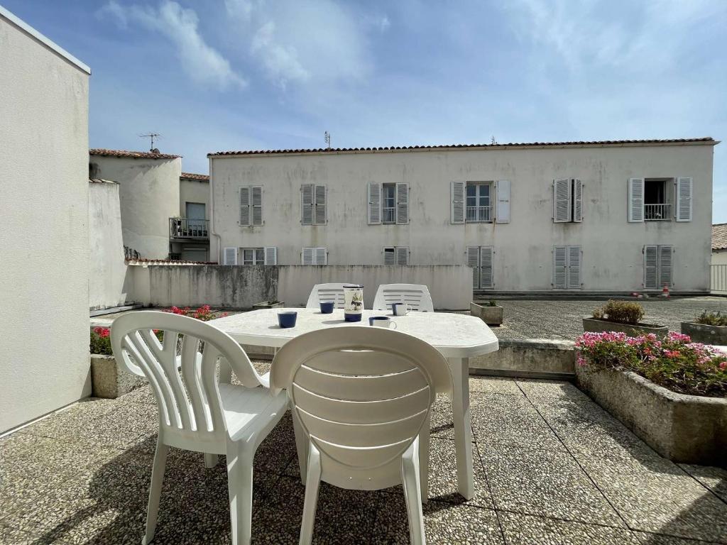 une table blanche et des chaises sur une terrasse dans l'établissement Appt 2 pièces ILE DE RE - SAINT MARTIN DE RE - IDR400-04D, à Saint-Martin-de-Ré