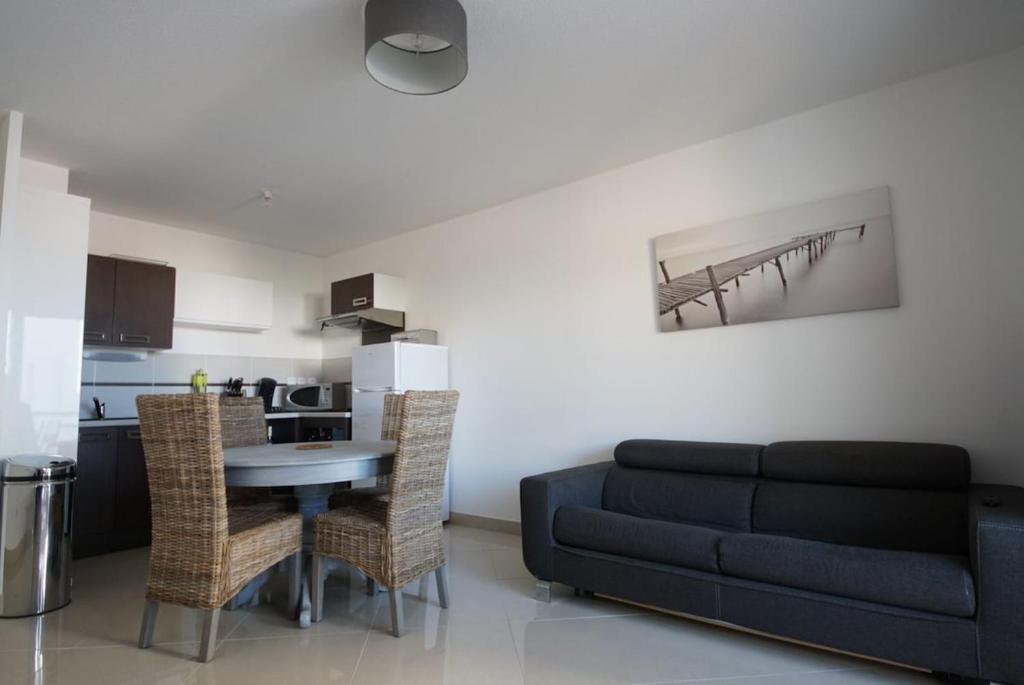 un salon avec un canapé et une table et une cuisine dans l'établissement T3 tout confort à 100m de la plage, Parking couvert gratuit, à Saint Pierre La Mer