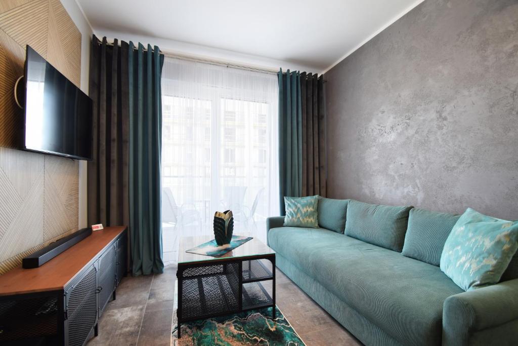 a living room with a green couch and a window at RentPlanet - Perłowa Przystań in Sianozety