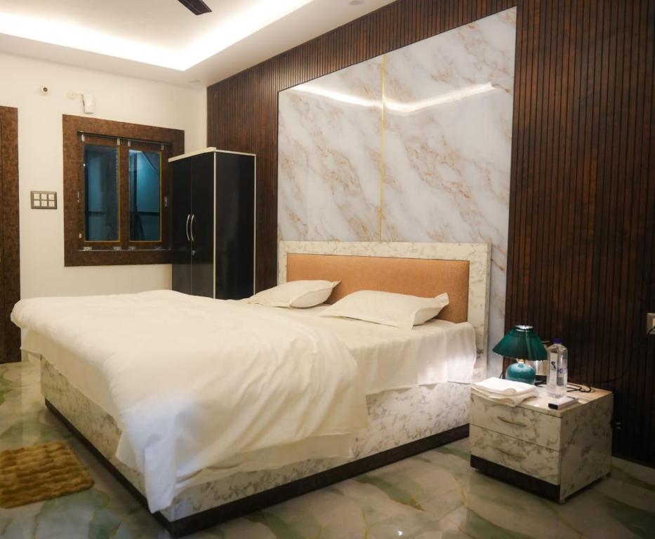 a bedroom with a large bed and a marble wall at Sapphire By the Ganges in Prayagraj