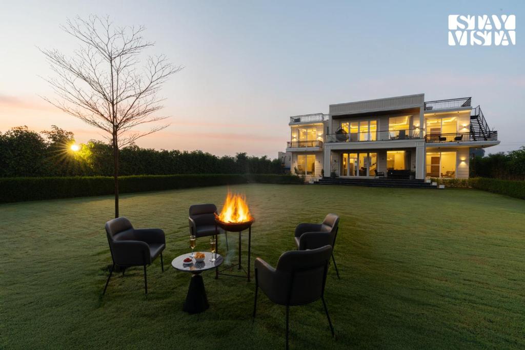 una casa con una hoguera en el patio en StayVista at Olive Farms with Lawn, Pool, Bonfire & Hill Views, en Mandkaula