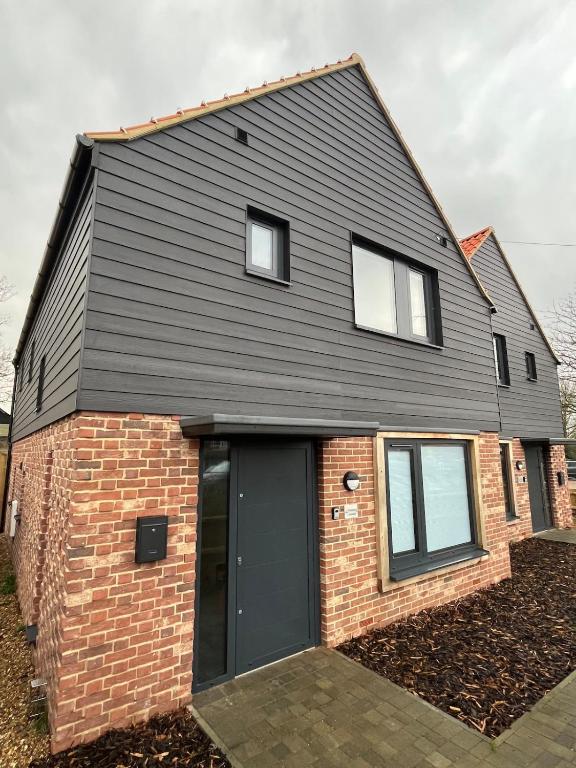 a house with a black roof and a brick at Pineapple Cottage in Thorndon