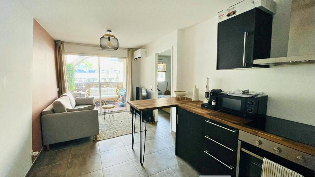 - une cuisine avec un bureau, un four micro-ondes et un canapé dans l'établissement T2 centre ville/Plage/Commerces/Clim, au Lavandou