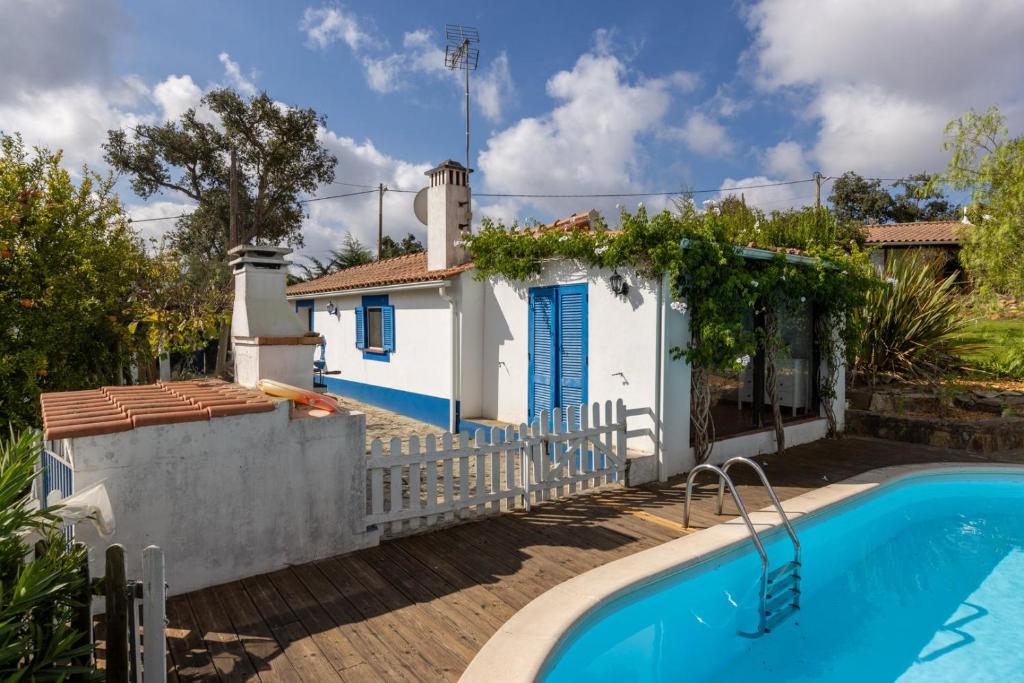a villa with a swimming pool in front of a house at Monte dos Casarões- Casinha in Odemira