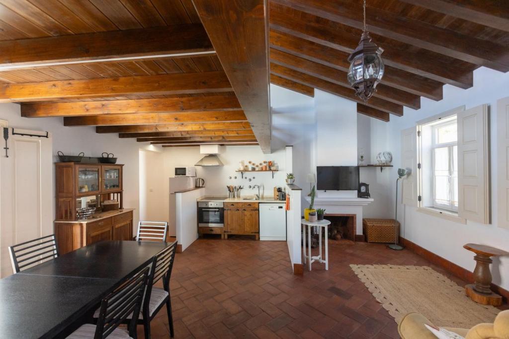 a living room with a table and a kitchen at Casa Amarela Sao Luis in Odemira