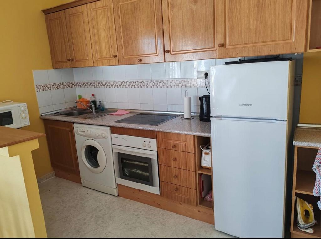a kitchen with wooden cabinets and a white refrigerator at Sandy Bunker 2 bed apartment and pool in Alicante