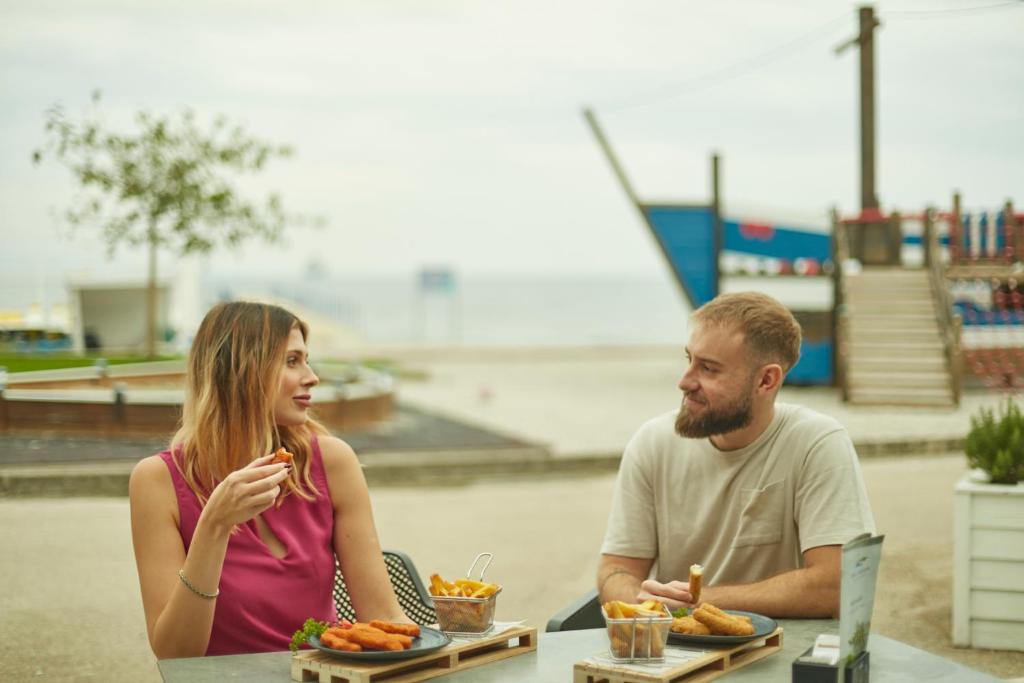 a man and a woman sitting at a table with food at Villas - Hotel & Resort Adria Ankaran in Ankaran