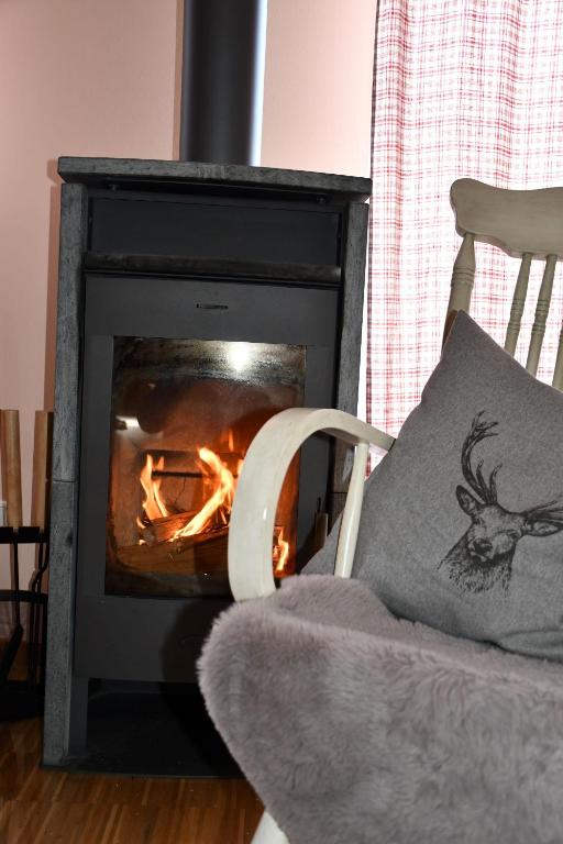 a fire burns in a fireplace with a pillow on a chair at Granerhof Ferien in Peißenberg
