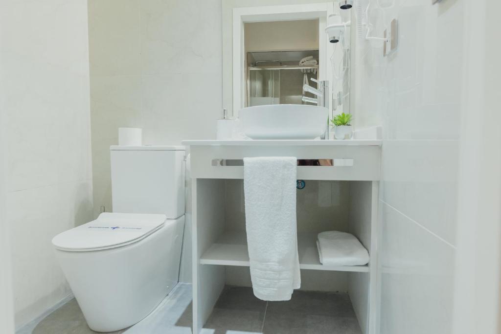 a white bathroom with a toilet and a sink at Olivae Hostal Boutique in Cáceres