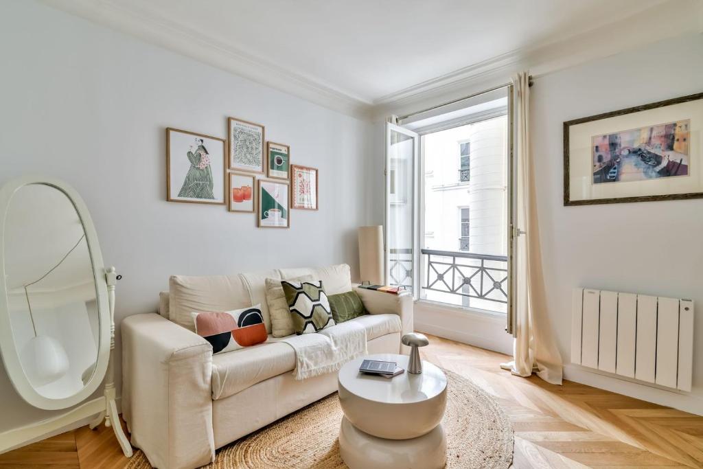 - un salon avec un canapé blanc et un miroir dans l'établissement Paris à Pied : Folies Bergère et Grands Boulevards, à Paris