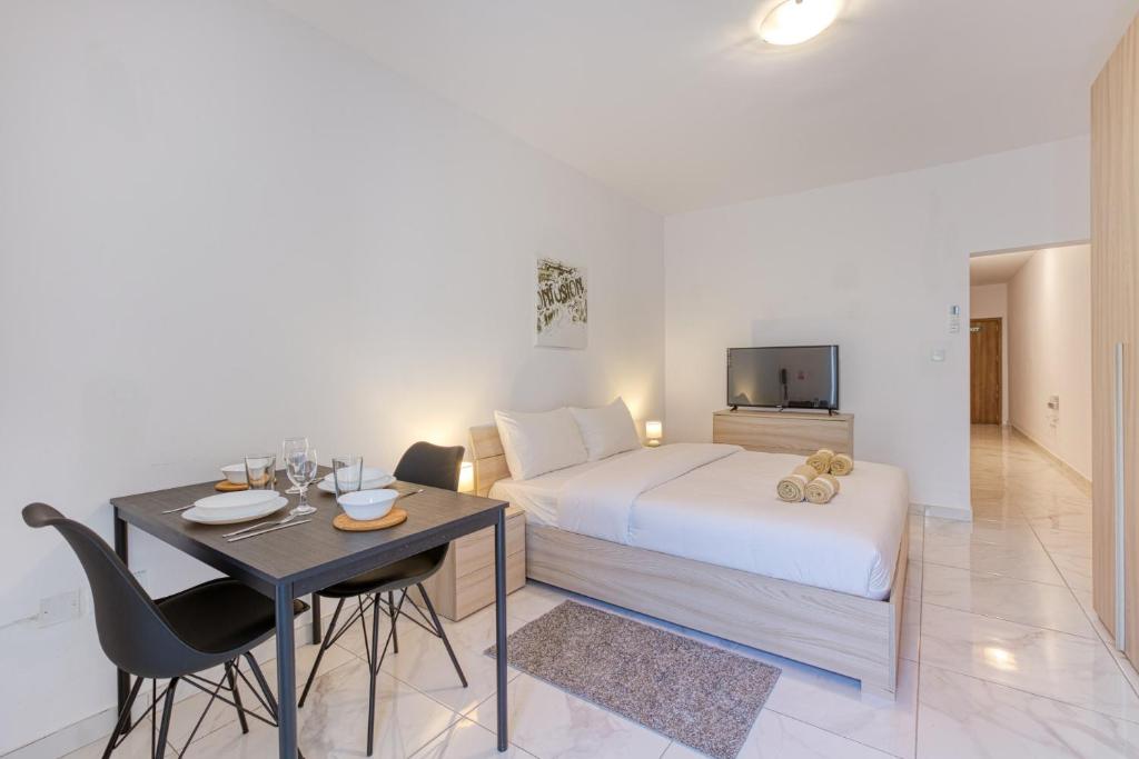 una camera d'albergo con un letto, un tavolo e una televisione di New Studio in Msida a Msida